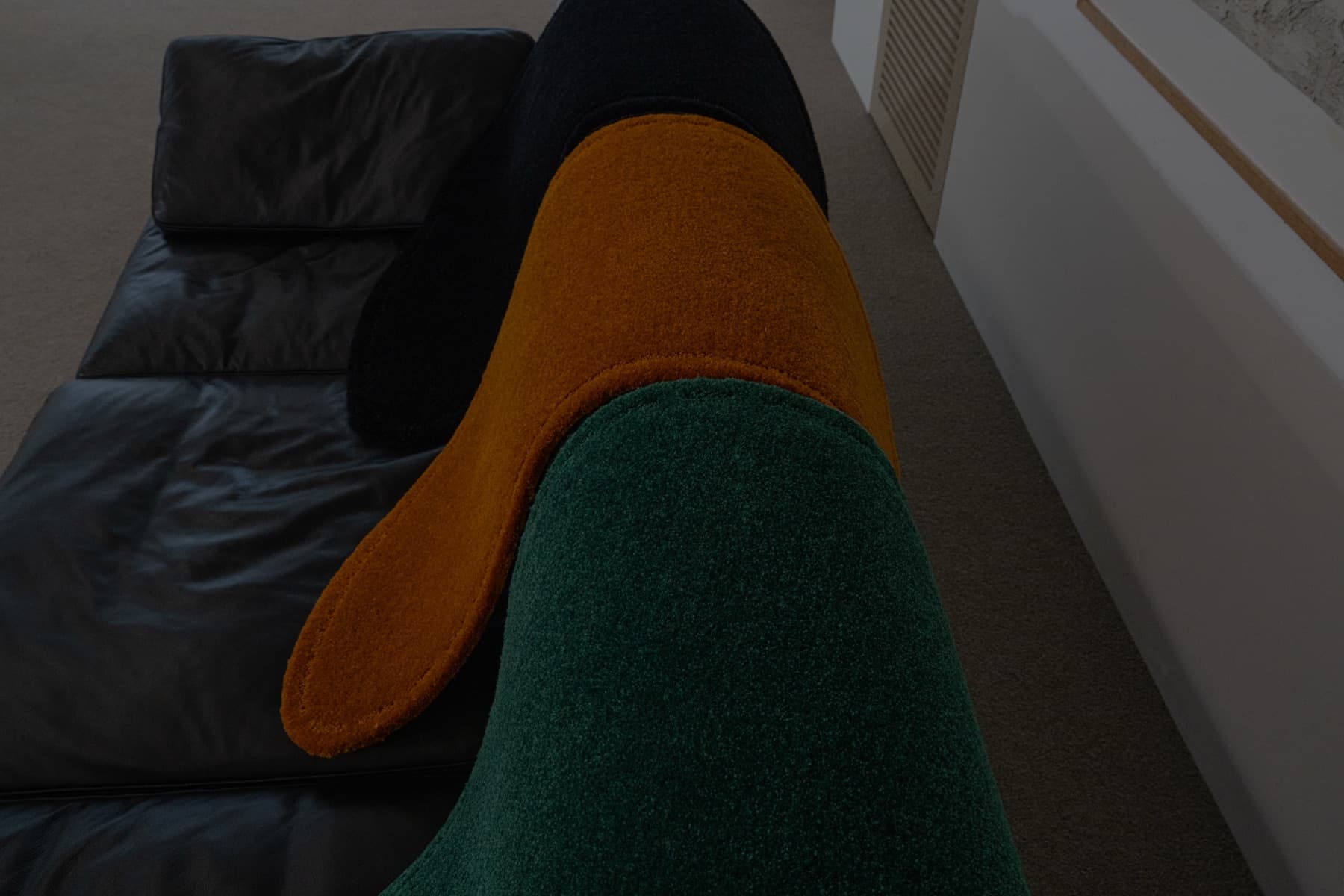 Black, ochre and green rugs draped over a leather sofa